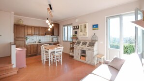 A spacious kitchen with wooden cabinets, a dining area with a wooden table and chairs, and a large window providing a view of greenery outside. - Nice apartment in Terranuova Bracciolini (Terranuova Bracciolini)