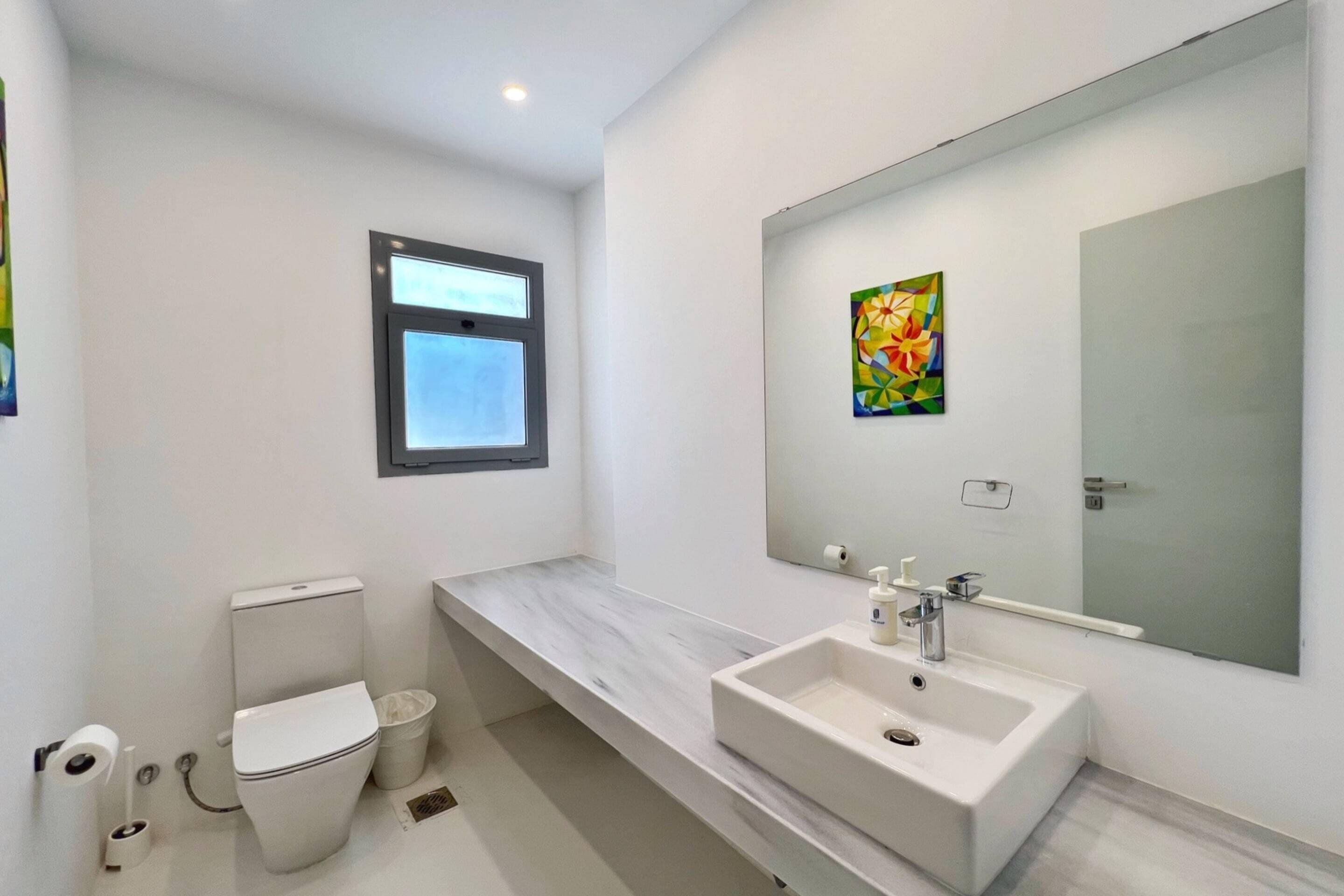 A modern bathroom with a toilet, sink, and window.