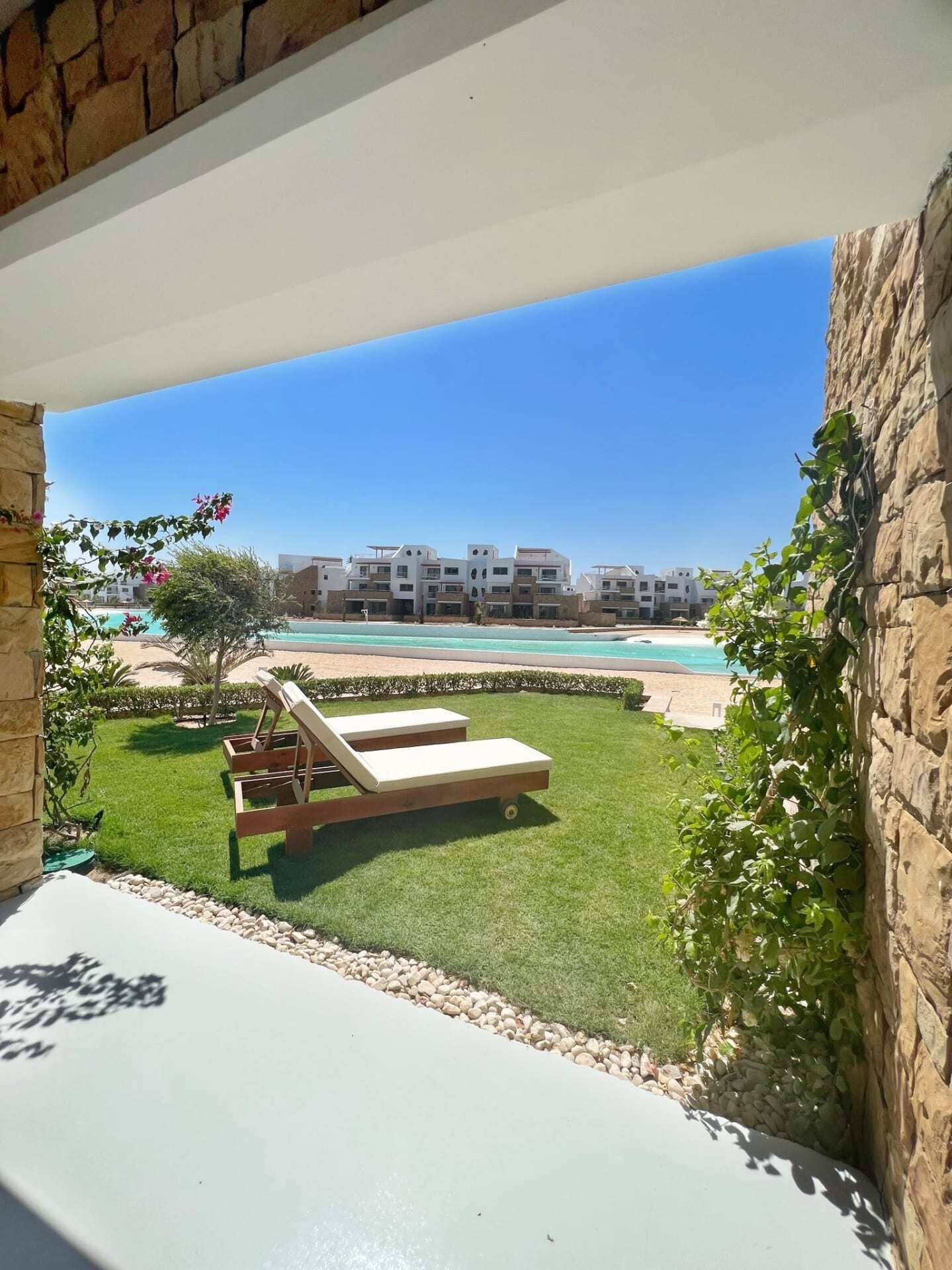 Un balcon donnant sur une piscine, des chaises longues et un ensemble d’immeubles en arrière-plan.
