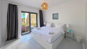 Un dormitorio moderno con una cama grande, una mesita de noche con lámpara y vistas a zonas verdes.