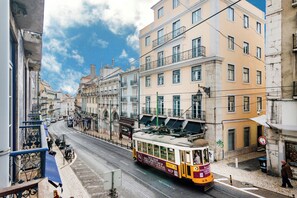 A tram on a street with buildings on both sides. - Chiado Mercy I (Lisbon)