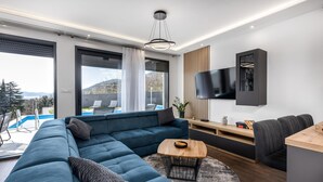 Un salon moderne avec un canapé d’angle, une table basse et un téléviseur fixé au mur.