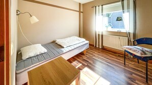 A small, well-lit room with a bed, a chair, and a table. - Nice apartment in Höör (Höör)