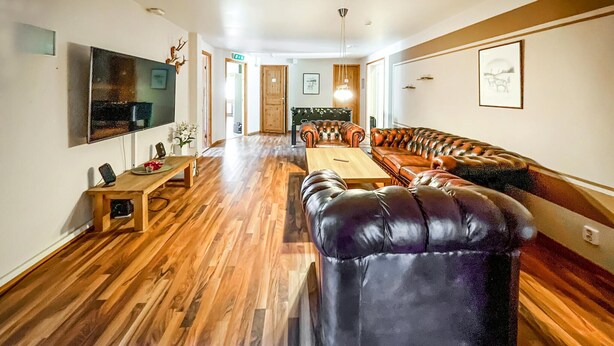 A spacious living area with a wooden floor, leather sofa, and a television mounted on the wall. - Nice apartment in Höör (Höör)