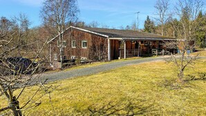 A rustic wooden building with a porch, a covered outdoor seating area, and a fenced yard. - Nice apartment in Höör (Höör)