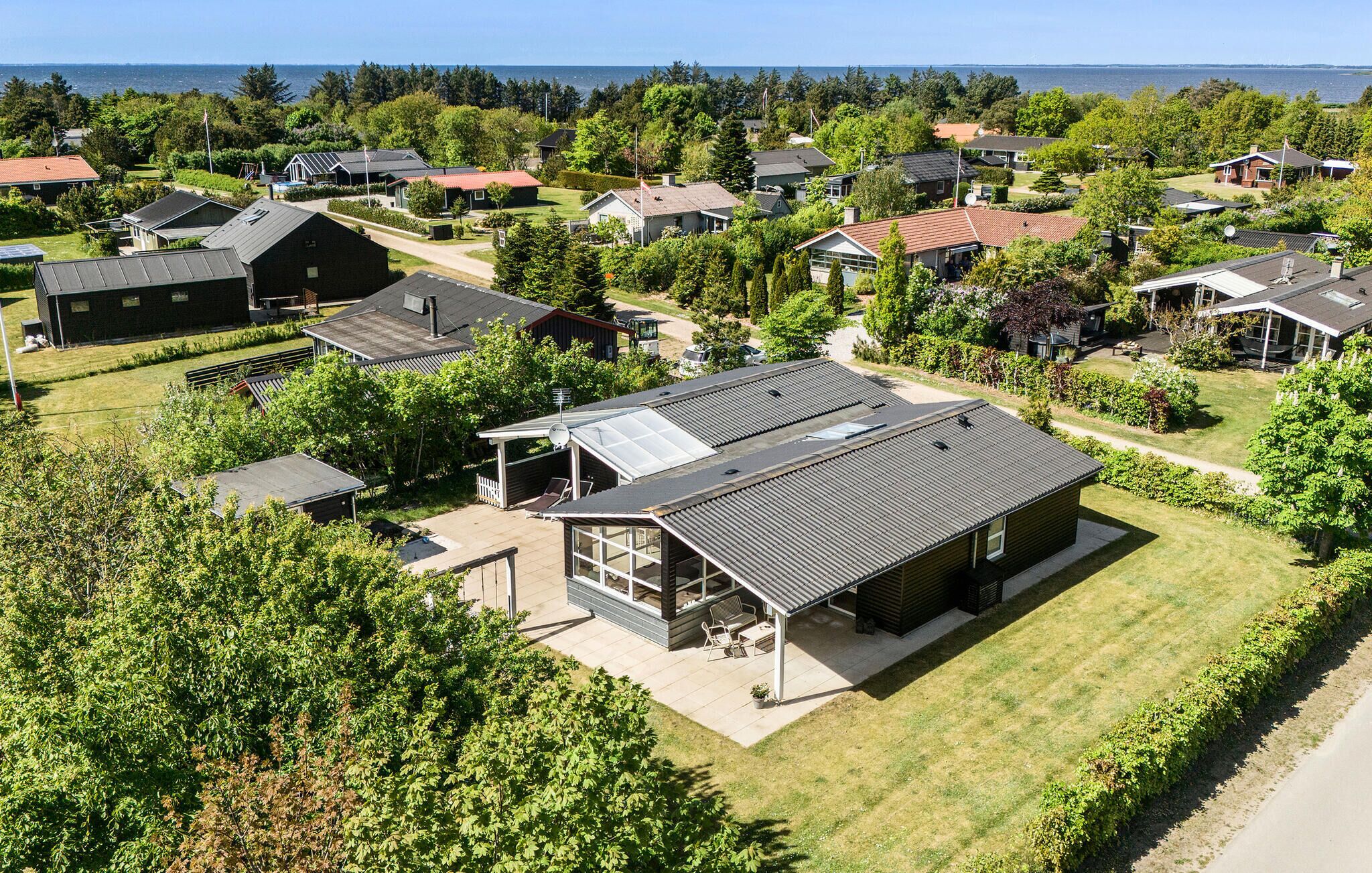A residential area with houses, a large house with a covered patio, and a view of the sea.