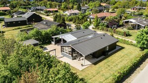 Ett bostadsområde med hus, ett stort hus med en inglasad uteplats och utsikt över havet.