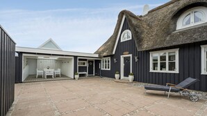 A thatched-roof building with a covered outdoor seating area and a paved courtyard.