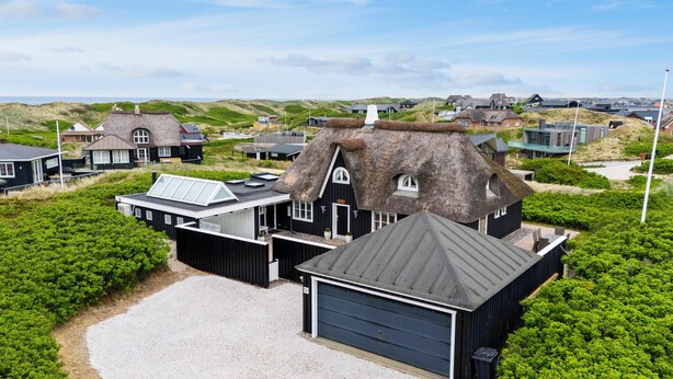 A thatched-roof house with a garage and a covered patio area.