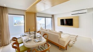 Een moderne woonkamer met een eethoek, een bank en een tv aan de muur.