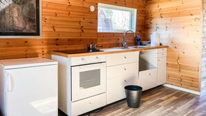 A compact kitchen with wooden walls, a sink, a stove, and a small refrigerator. - 1 bedroom cozy home in Huaröd (Huaröd)