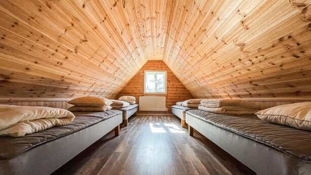 A cozy attic bedroom with two single beds, wooden slats on the ceiling, and a window at the peak. - 1 bedroom cozy home in Huaröd (Huaröd)