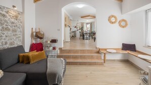 Un vaste espace de vie agrémenté d’un mur en pierre, d’un plafond en bois et d’un escalier menant à une salle à manger.