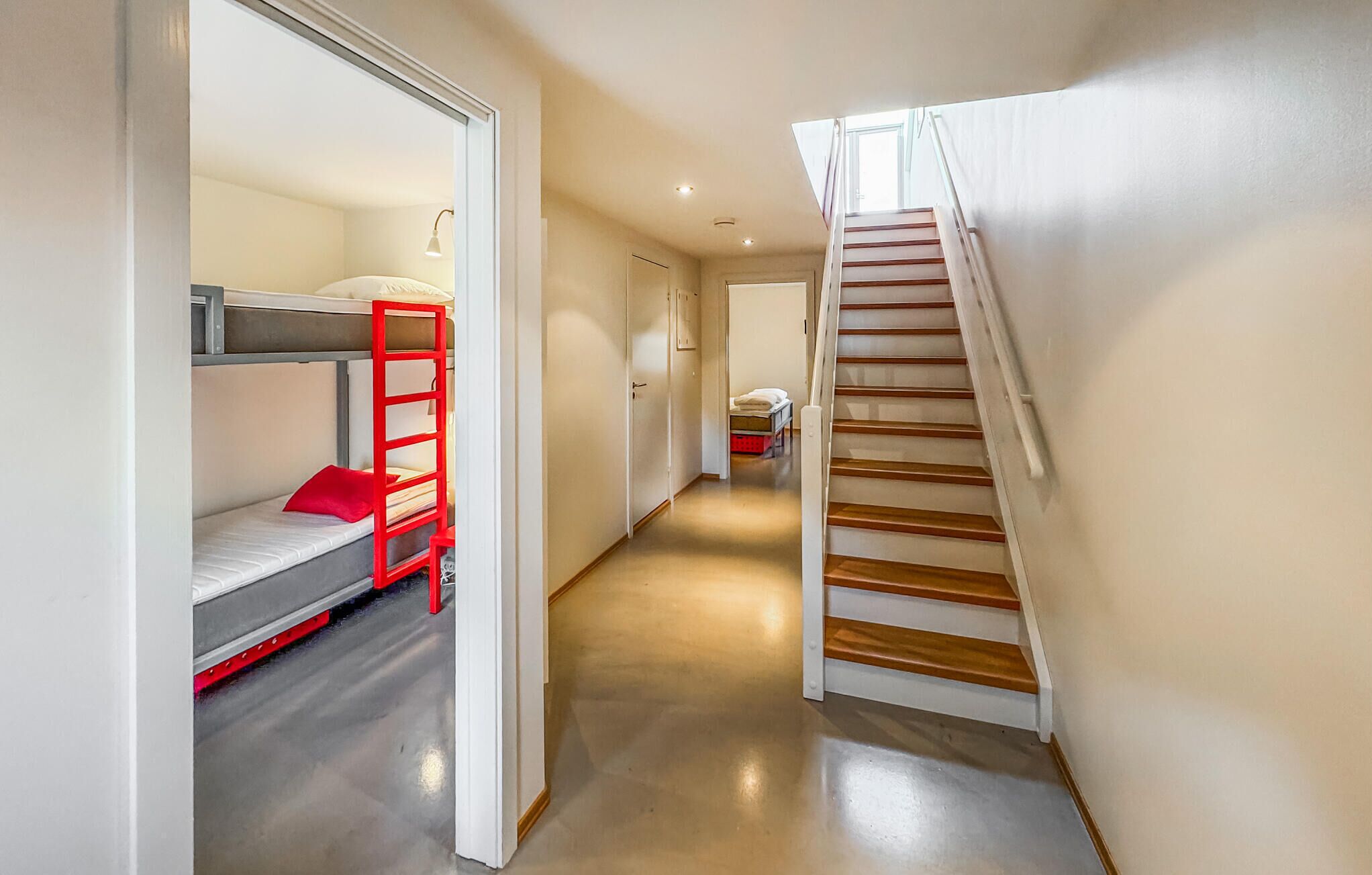 En smal hall med en våningssäng på vänster sida och en trätrappa på höger sida.