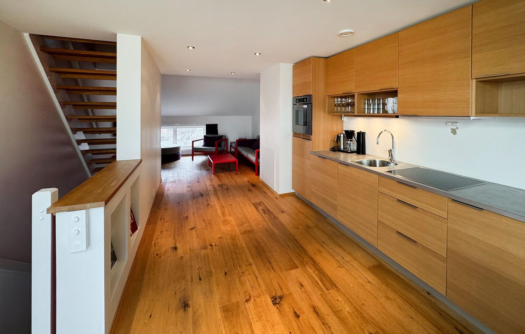 Una cocina moderna con armarios de madera, un lavamanos de acero inoxidable y un horno empotrado.
