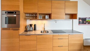 A modern kitchen with wooden cabinets, a built-in oven, a stainless steel sink, and a coffee maker. - Amazing apartment in Søgne with WiFi (Søgne)