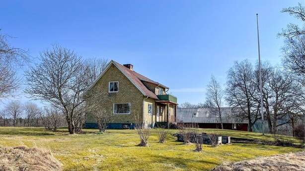 A two-story house with a gabled roof, a front porch, and a small balcony.