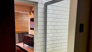 Ein Zimmer mit einer Schiebetür und Zugang zu einer Küche mit weißen Fliesen im U-Bahn-Stil und einem Holzkorpus.