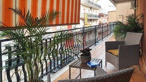 A balcony with wicker furniture, a table, and potted plants.
