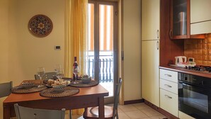 A compact kitchen with a dining area, a small balcony, and a decorative plate on the wall.