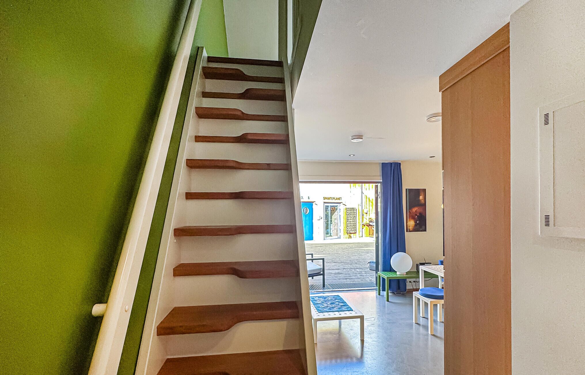A staircase with wooden steps leading to a room with a view of the street.