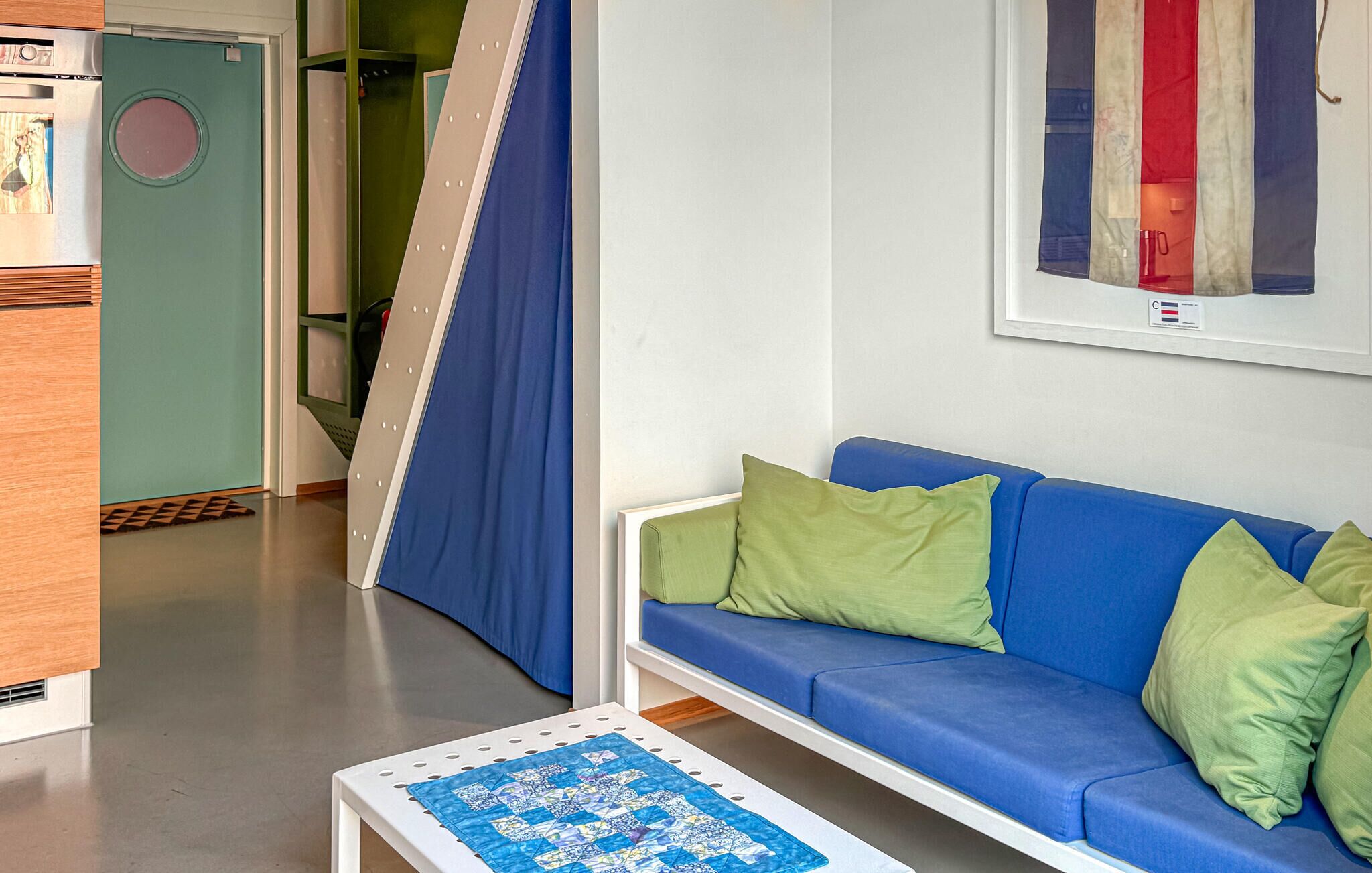 A modern living room with a blue sofa, green pillows, and a quilted table.
