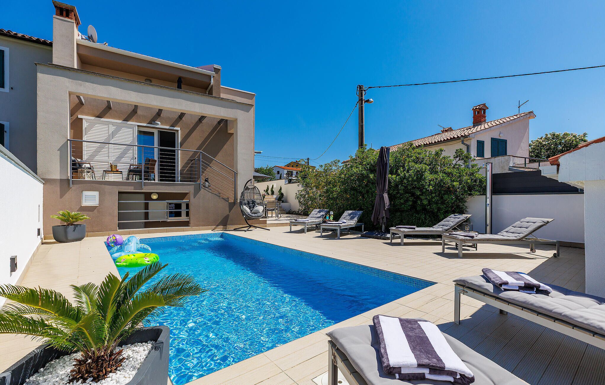A swimming pool with lounge chairs and a small garden area.