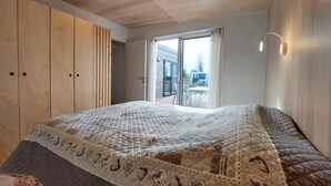 A bedroom with a large bed, wooden wardrobe, and a sliding glass door leading to an outdoor area. - 2 bedroom beautiful home in Ambon (Ambon)