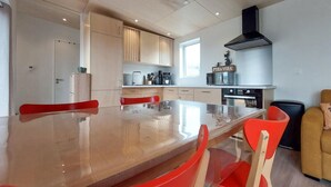 A modern kitchen with a large island, red chairs, and a black range hood. - 2 bedroom beautiful home in Ambon (Ambon)