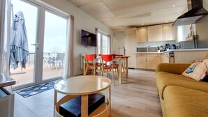 A modern living room with a yellow sofa, a round coffee table, and a dining area with red chairs. - 2 bedroom beautiful home in Ambon (Ambon)