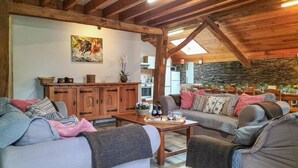 Ein gemütliches Wohnzimmer mit Holzmöbeln, einer Steinwand und einem Gemälde von Pferden.