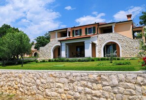 Una casa de piedra de dos pisos con fachada de piedra, techo de tejas y césped bien cuidado.
