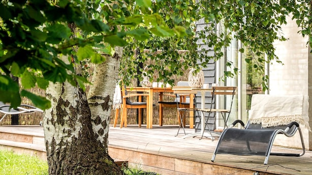 Une terrasse en bois avec une table et des chaises, un banc et un barbecue.