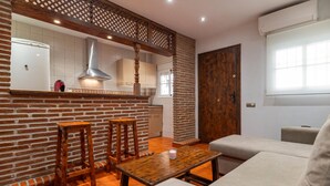 A modern kitchen with a brick accent wall, wooden stools, a dining table, and a large window.