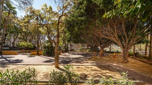 A park with trees, benches, and exercise equipment.