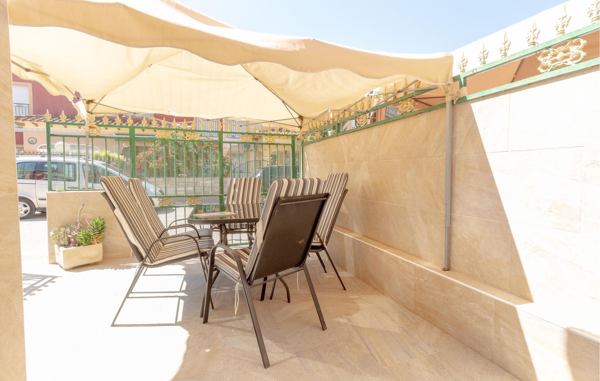 Une terrasse extérieure avec une table et des chaises, une plante en pot et un mur décoratif.