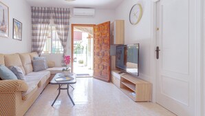 A living room with a sofa, a coffee table, a TV, and a wooden door.