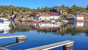 A calm harbor with boats docked, a wooden pier, and houses with red roofs on a hillside. - 2 bedroom pet friendly apartment in Søgne (Søgne)