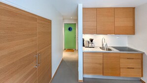 A modern kitchen with wooden cabinets, a green door, and a stainless steel sink. - 2 bedroom pet friendly apartment in Søgne (Søgne)