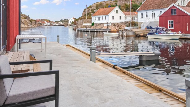 A waterfront dock with a wooden walkway, a red building, and white houses in the background. - 2 bedroom pet friendly apartment in Søgne (Søgne)