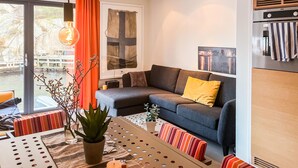 A modern living room with a sofa, a dining table, and a potted plant. - 2 bedroom pet friendly apartment in Søgne (Søgne)