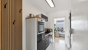 A modern kitchen with a built-in oven, microwave, and a coffee maker on the countertop.