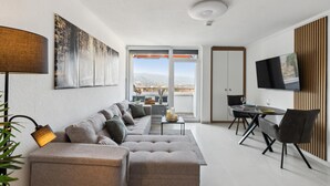 A modern living room with a sofa, a dining table, and a TV.