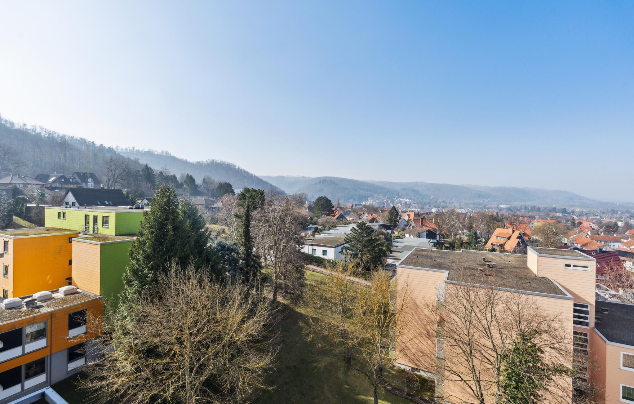 Un quartier résidentiel avec des bâtiments modernes, une vue dégagée sur le paysage environnant et une ville située au loin.