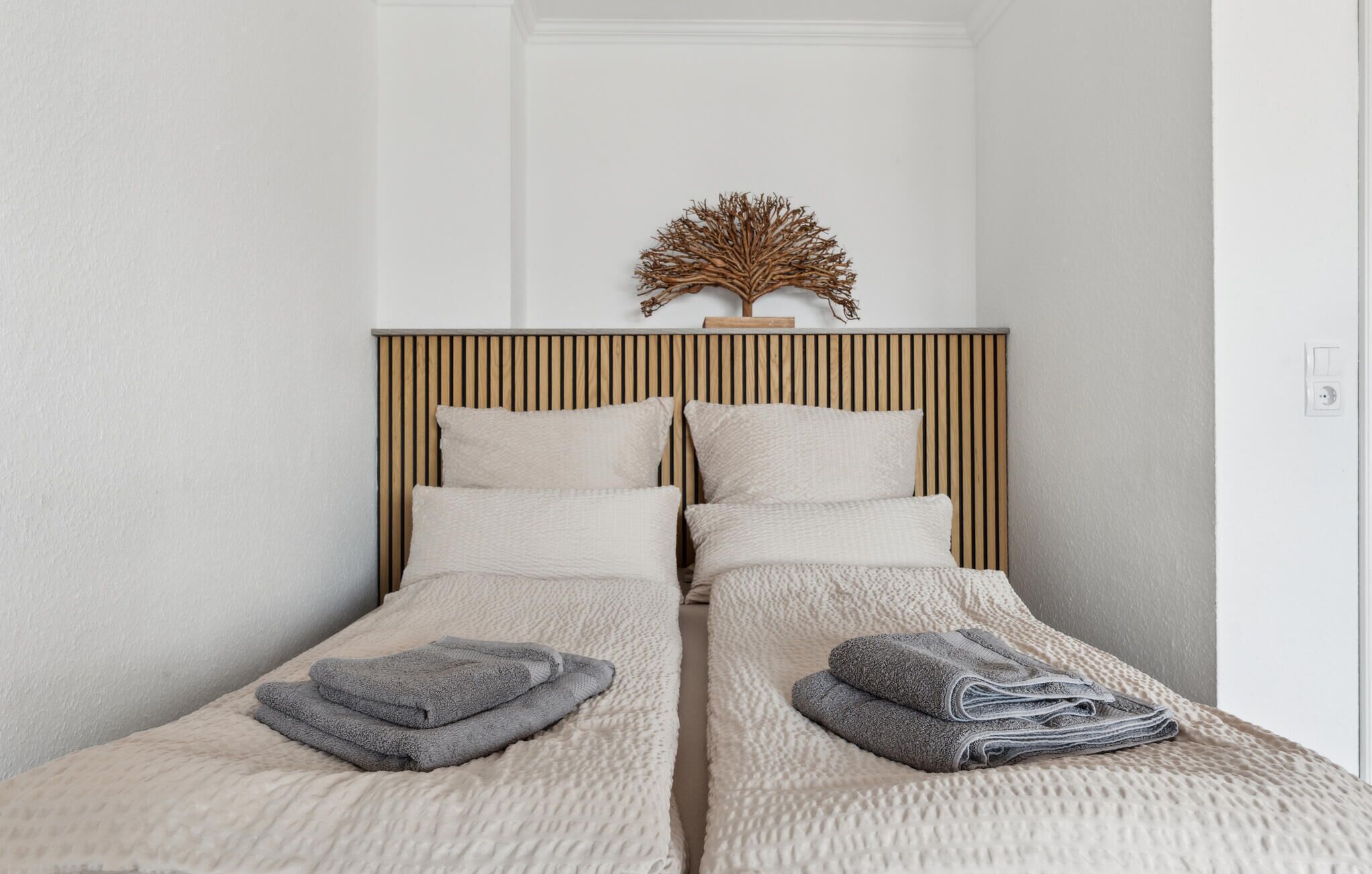 Ein Doppelbett mit Holzüberbau, zwei Kissen und gefaltete Handtücher.