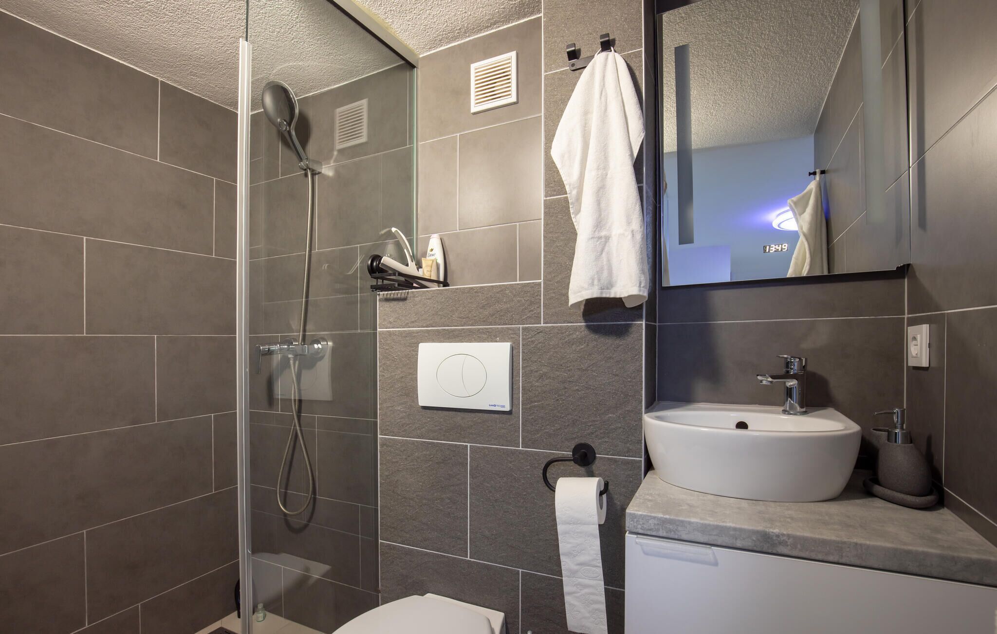 Un baño moderno con cabina de ducha de vidrio, un lavabo blanco y un espejo sobre él.