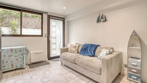 Ein Wohnzimmer mit einem beigen Sofa, einem kleinen Tisch und einem dekorativen Regal.