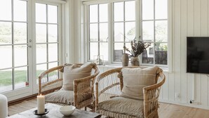 A room with two wicker chairs, a table with a candle, and a vase with dried flowers on a window sill. - Cozy home in Nordborg with WiFi (Nordborg)