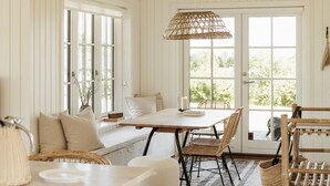 A cozy room with a large window, a wooden table, wicker chairs, and a hanging light fixture. - Cozy home in Nordborg with WiFi (Nordborg)
