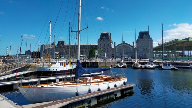 A marina with boats docked, a large building with a distinctive roof, and a covered area with a green roof. - Awesome apartment in Oostende (Oostende)